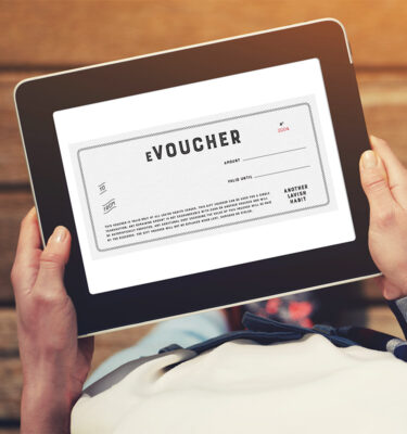Photo of a woman in a check shirt holding an iPad with a voucher on the screen